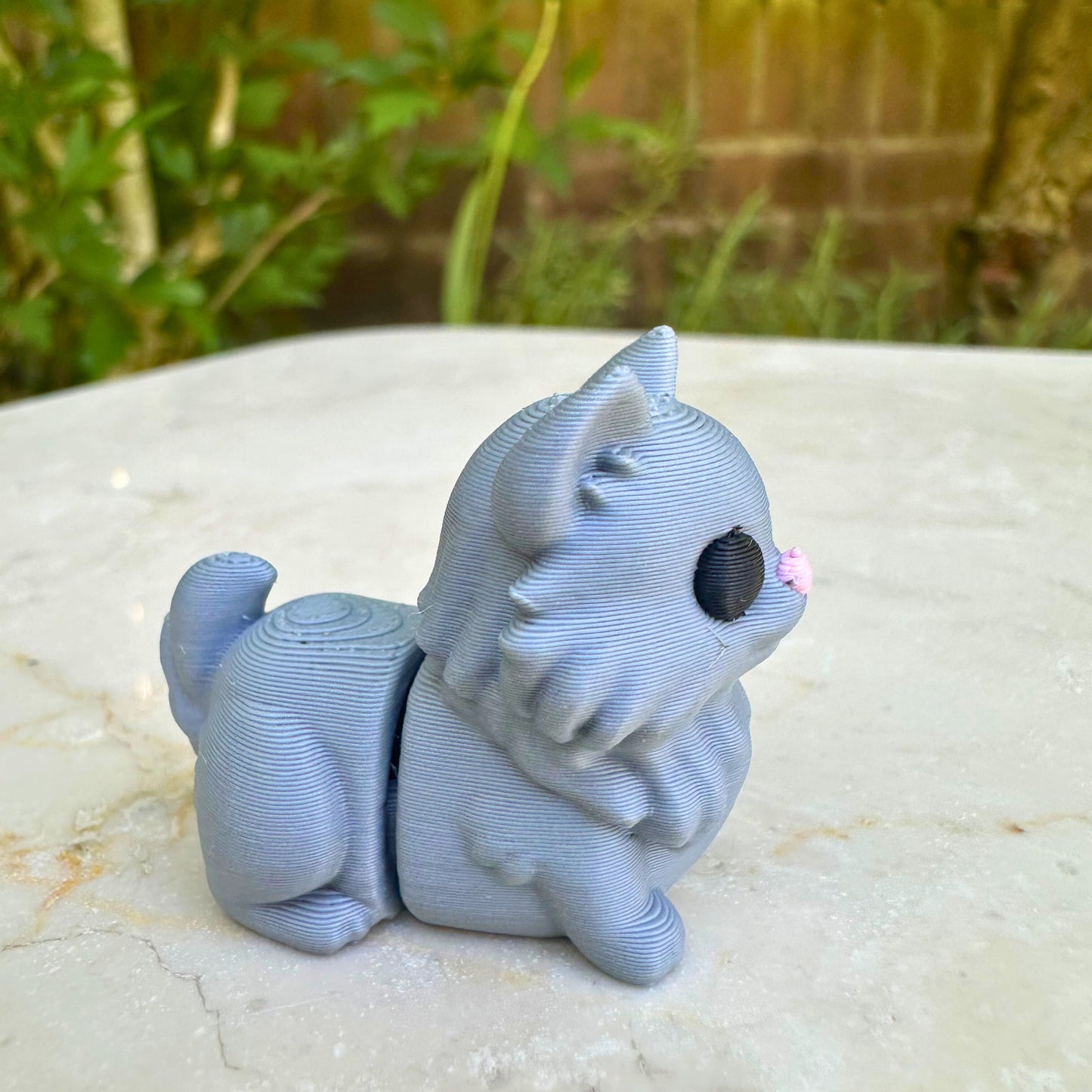 Zijaanzicht van 3D geprint grijs flexi katje, toont beweegbare segmenten, eco-vriendelijk speelgoed.