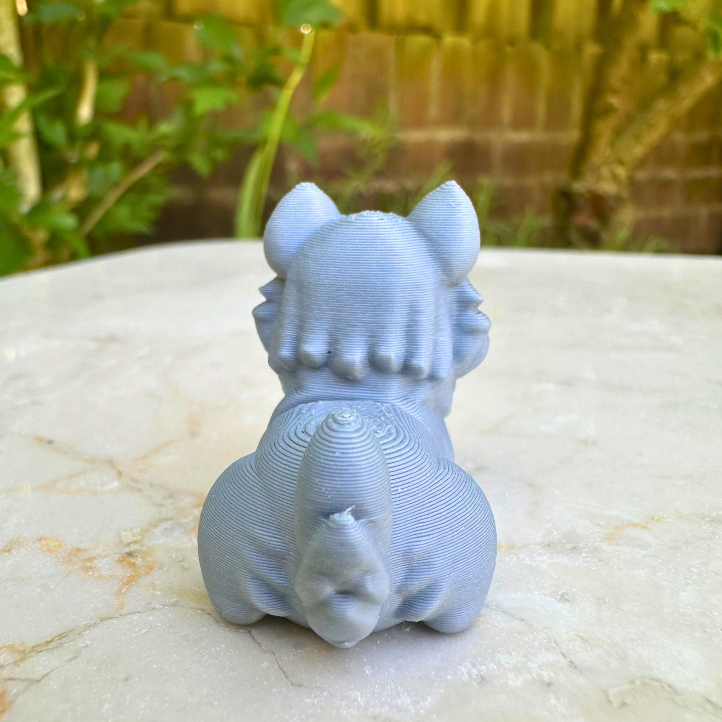 Achteraanzicht van het grijze 3D geprinte speelgoed katje met flexibele staart, gemaakt van duurzaam maiszetmeel.