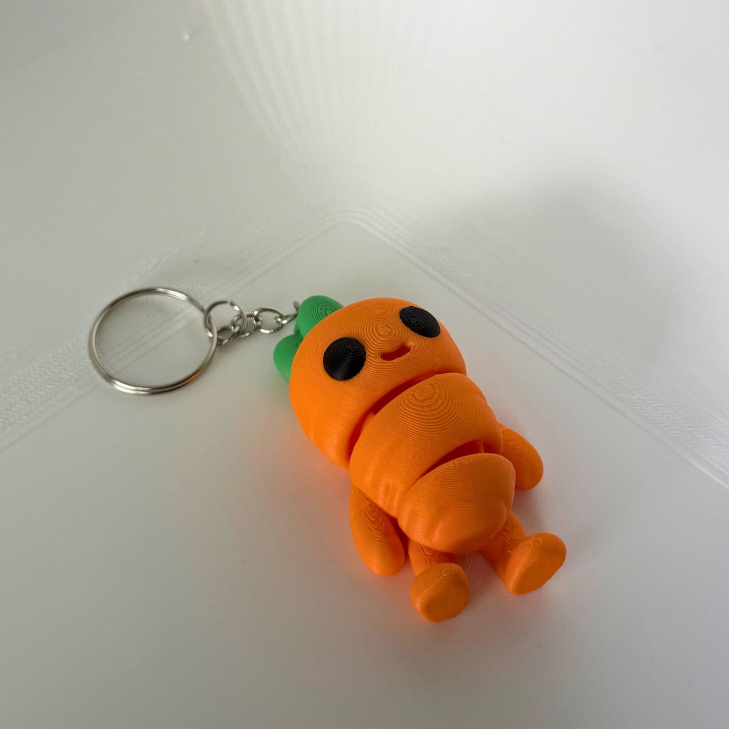 3D-geprint wortel figuur met sleutelhanger – PLA speelgoed in oranje en groen, liggend vooraanzicht
