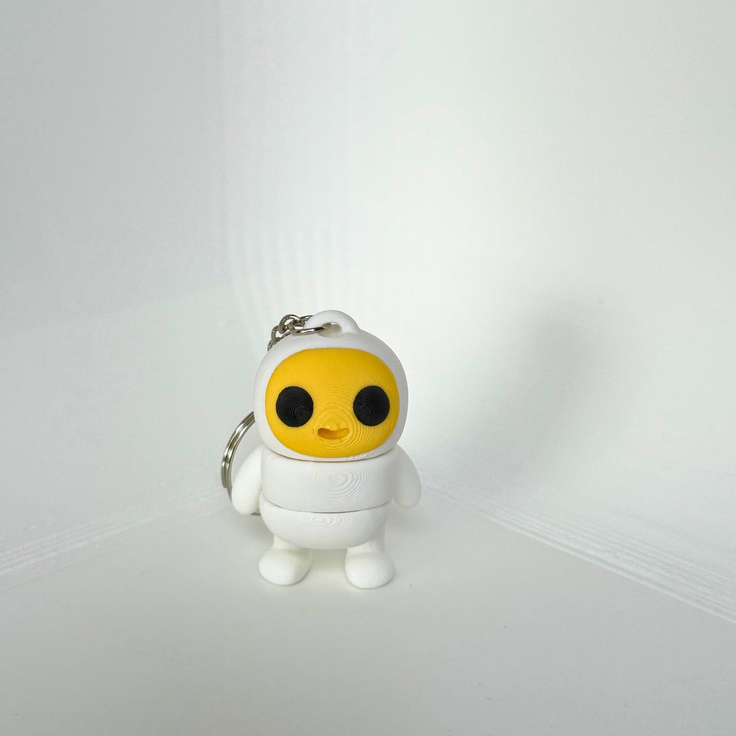 Kindvriendelijke sleutelhanger van Egg Boy – een schattig 3D-geprint figuur met een geel gezicht en witte outfit.