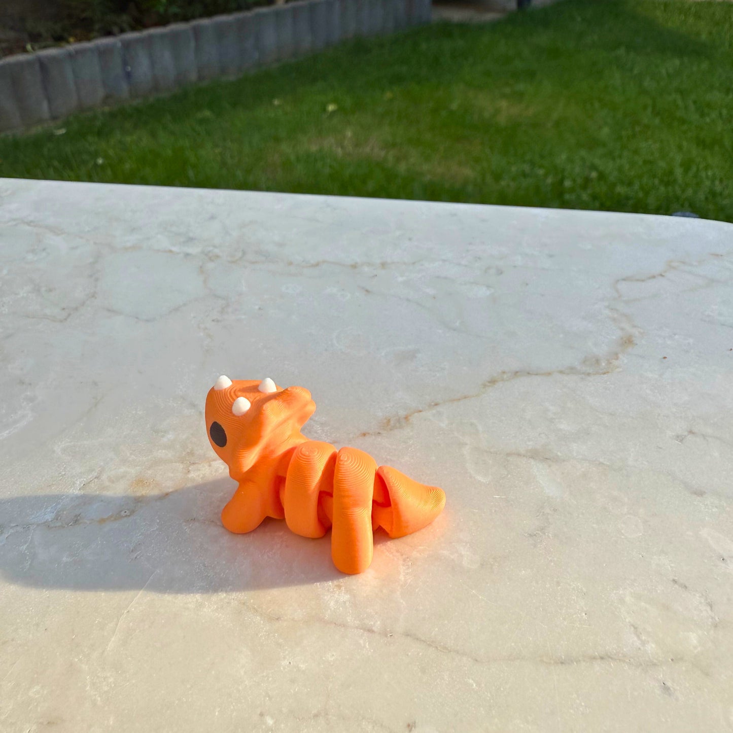 Detail van een 3D geprinte flexibele baby triceratops, focus op het nekschild en de hoorntjes.