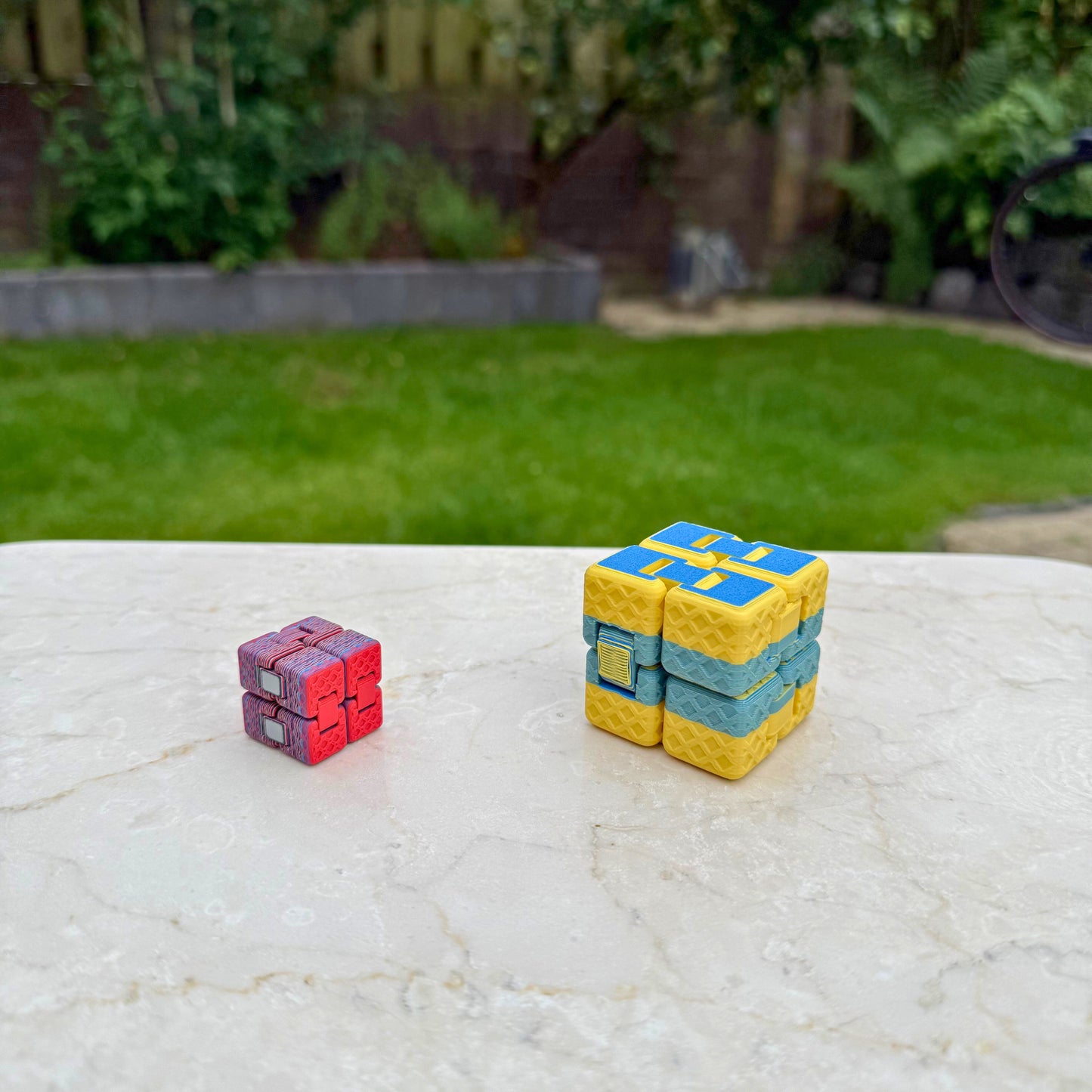 Twee 3D geprinte eindeloze fidget kubussen (infinity cubes) in verschillende maten en kleuren.