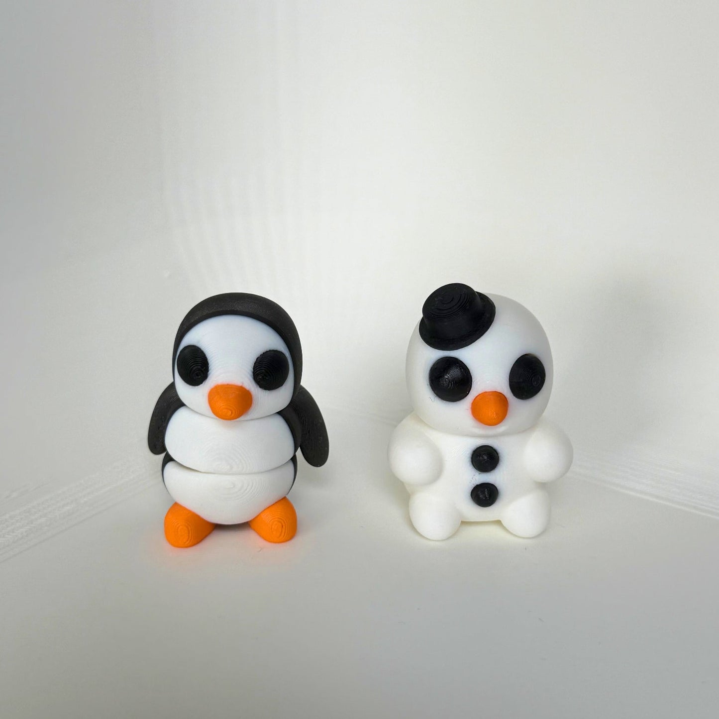 Kindvriendelijk speelgoed: 3D-geprinte pinguïn en sneeuwpop figuren met oranje neuzen, winterthema speelfiguren