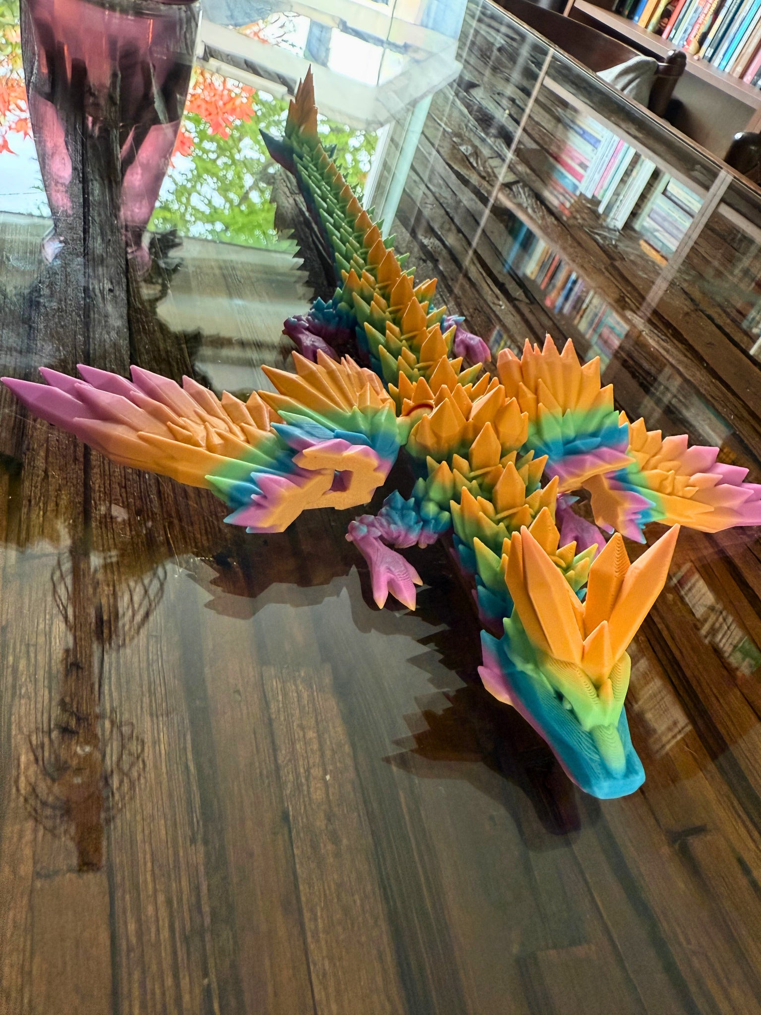 Grote regenboogdraak van dichtbij gezien vanaf de achterkant, met kleurrijke schubben en vleugels.