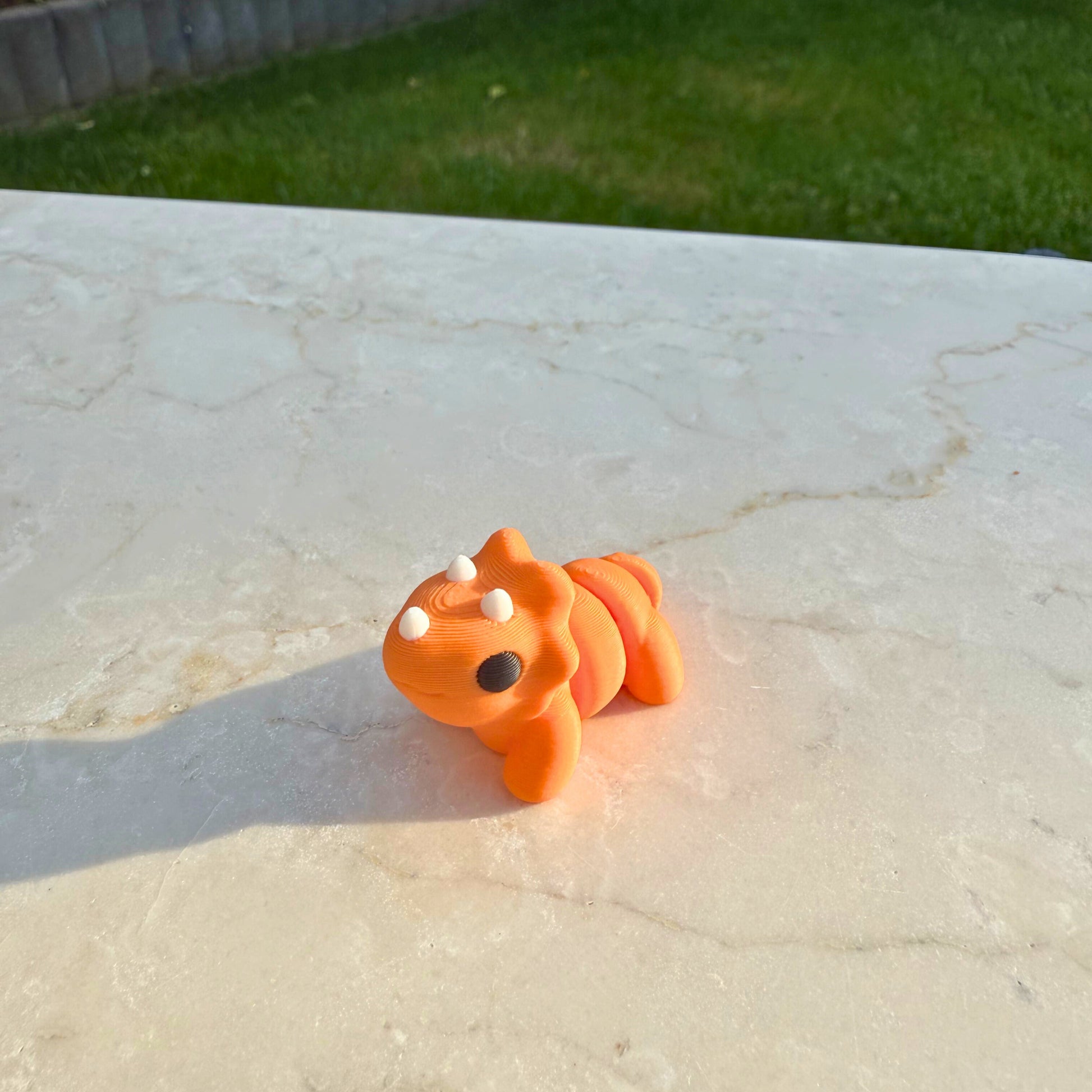 Schattig 3D geprint speelgoed baby triceratops, toont de articulatie en details van de drie hoorns.