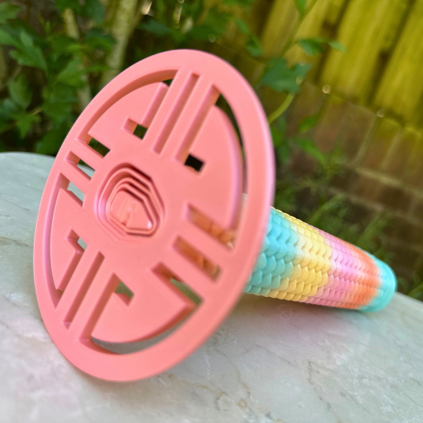 Detail van de roze stootplaat en het begin van het regenboog "drakenhuid" handvat van de uitschuifbare 3D speelgoed katana.