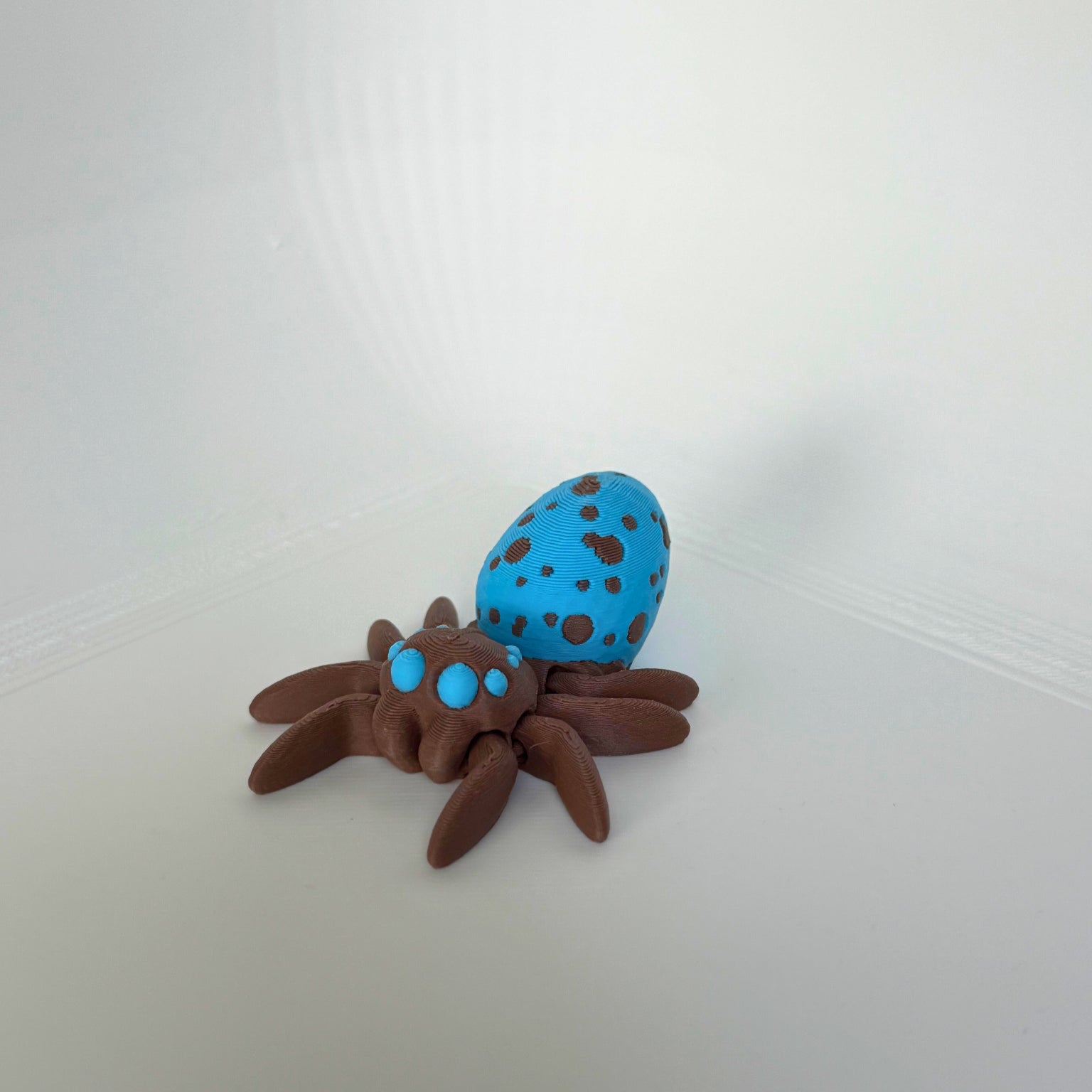 Articulated brown spider with bright blue spots on its back, displayed from a side angle.