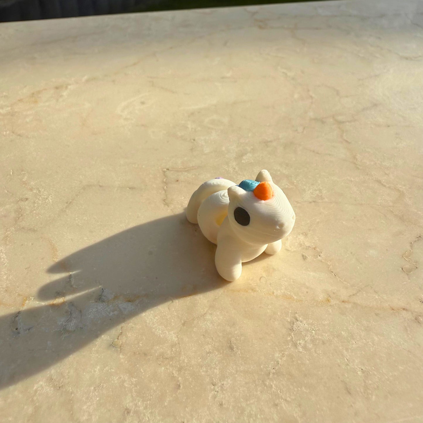 Zijaanzicht van een 3D geprinte flexibele eenhoorn (licorne), toont de elegante vorm.