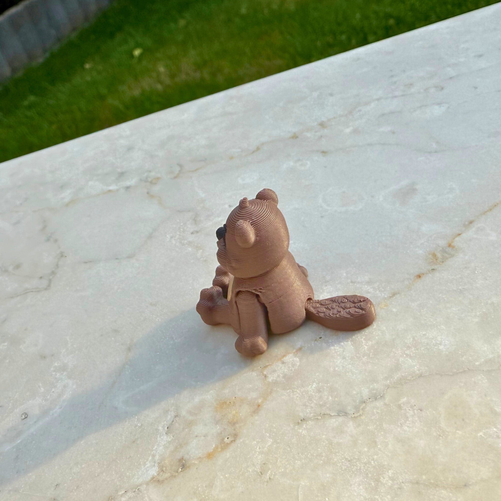 Speelgoedfiguur van een 3D geprinte flexibele bever, klaar voor avontuur in het bos.