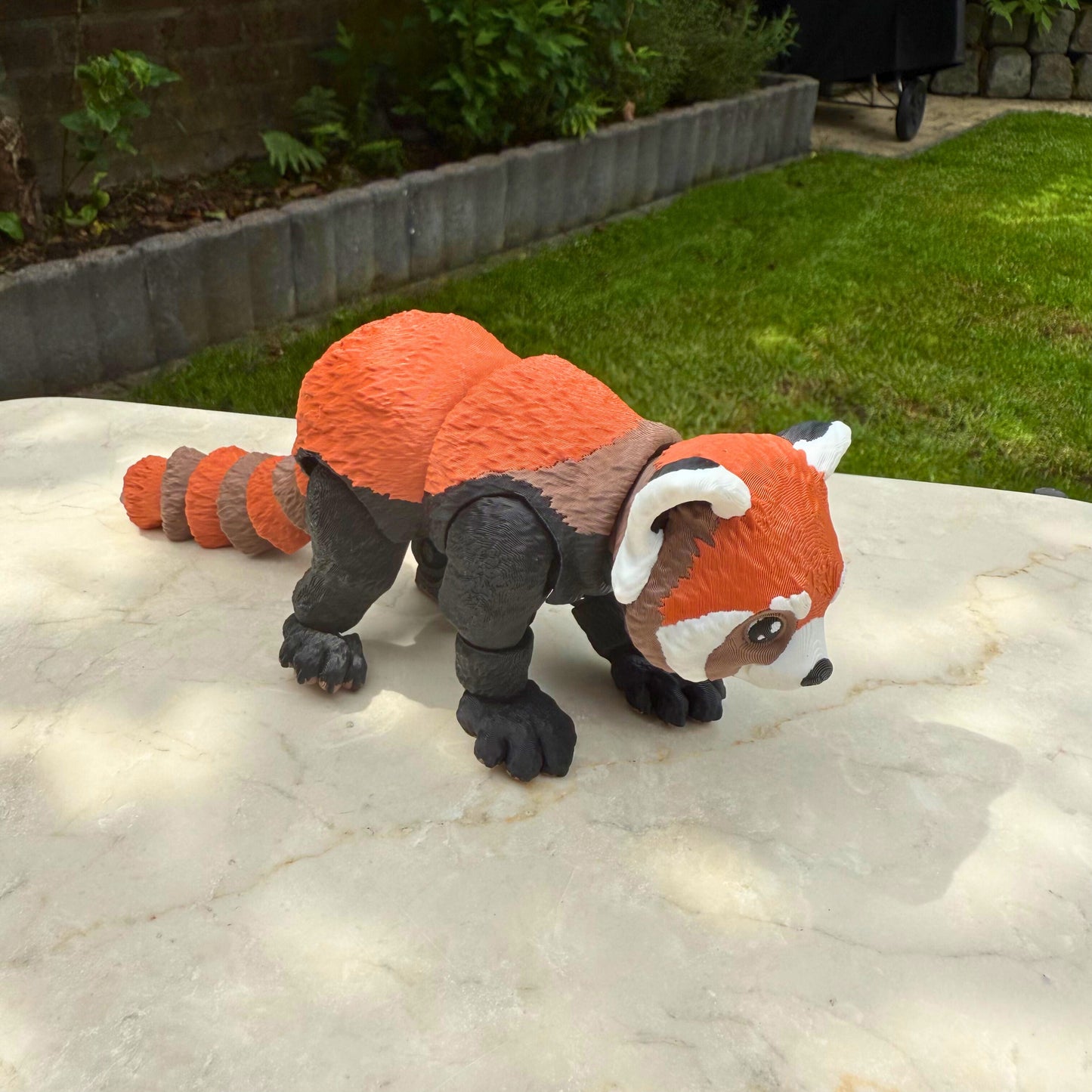 Staande 3D geprinte flexibele rode panda, toont de beweegbare poten en het gedetailleerde ontwerp.