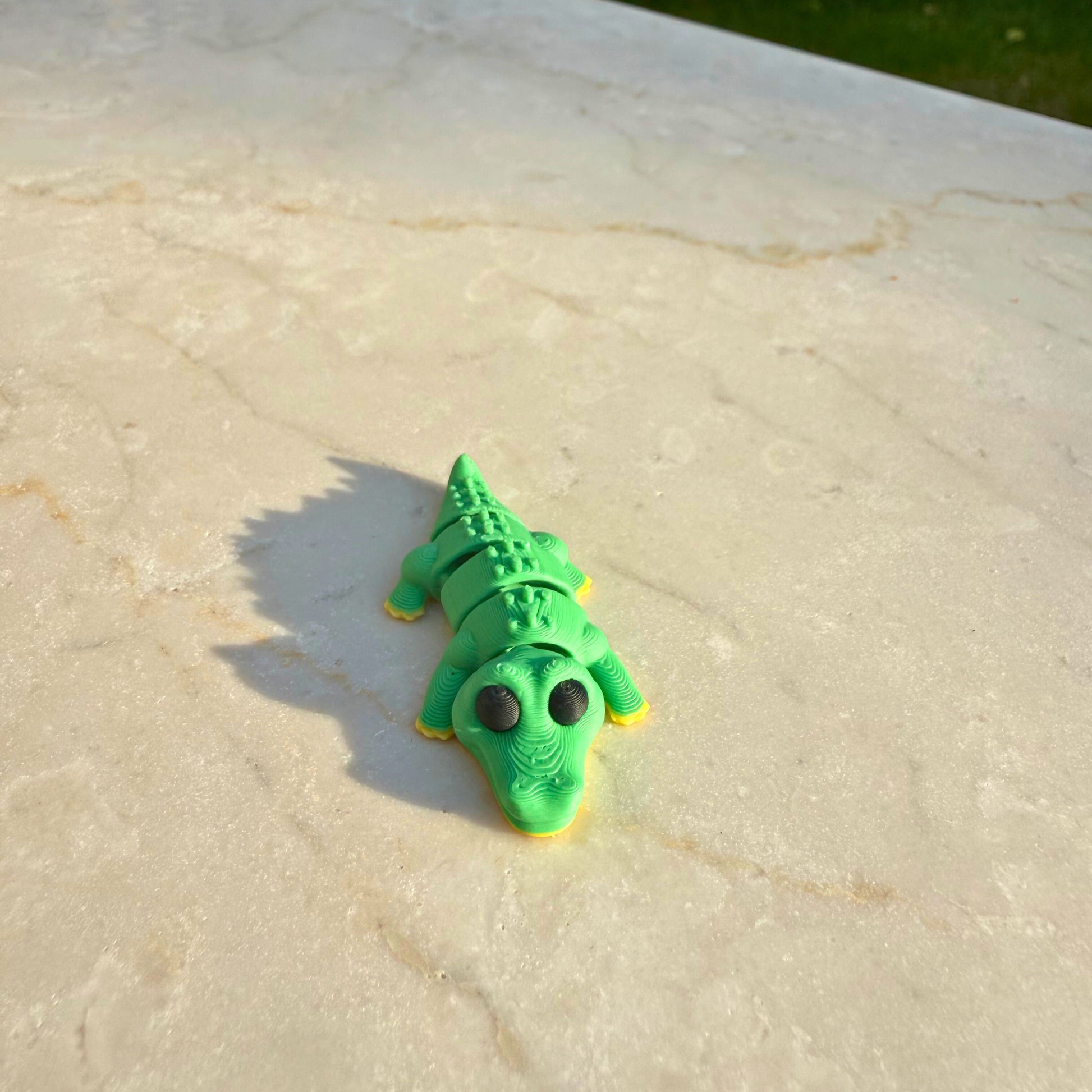 Detail van een 3D geprinte speelgoed krokodil, toont de articulatie en het geschubde lichaam.