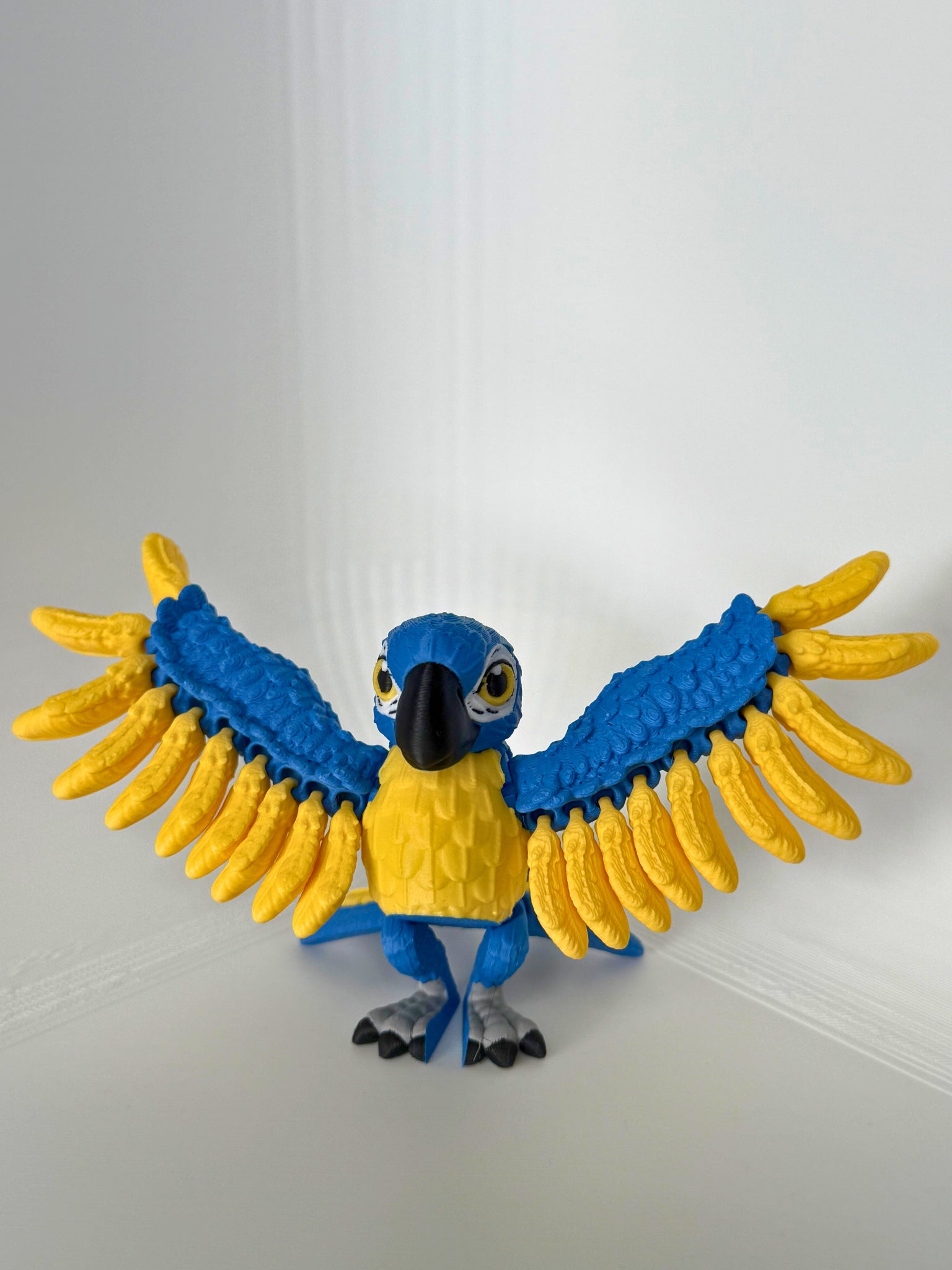 Speelse papegaai met uitgespreide blauwe en gele vleugels, perfect voor kindvriendelijk milieuvriendelijk speelgoed.