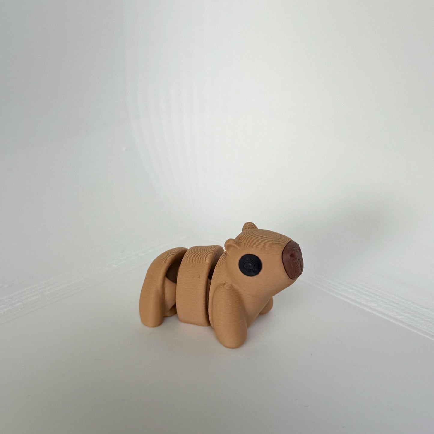 Bruine 3D-geprinte capibara met zwart-neus detail, liggend op zijn buik.