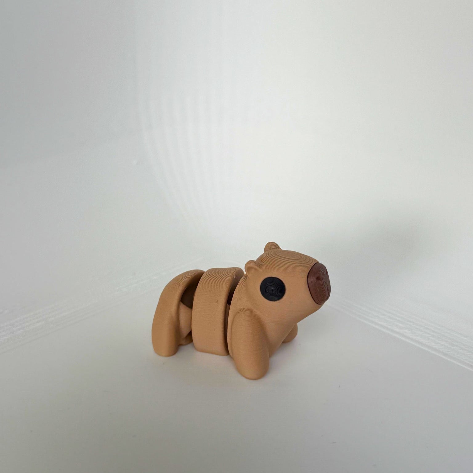 Bruine 3D-geprinte capibara met zwart-neus detail, liggend op zijn buik.