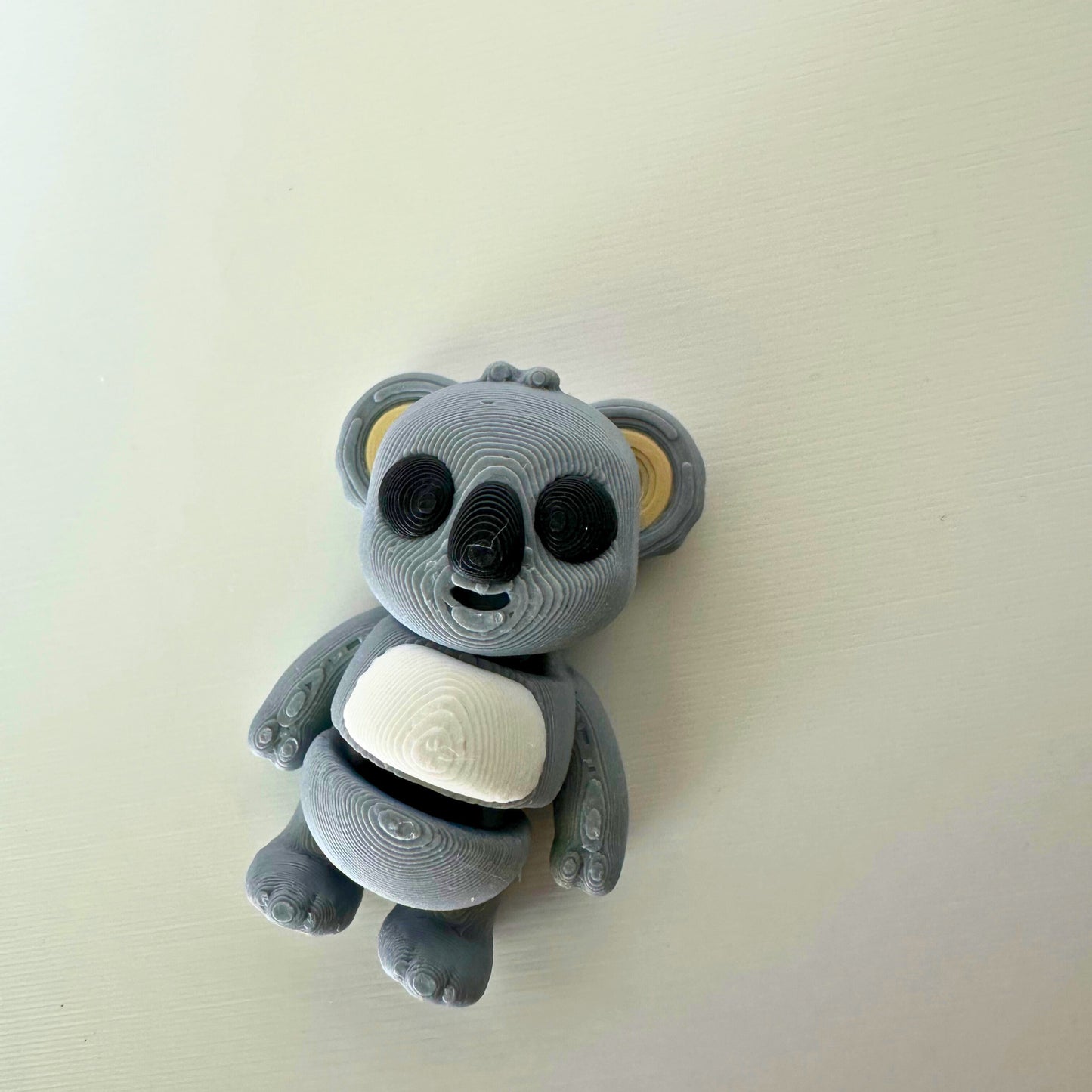 Duurzaam speelgoed: grijs koala figuur met zwarte ogen en witte buik, vooraanzicht