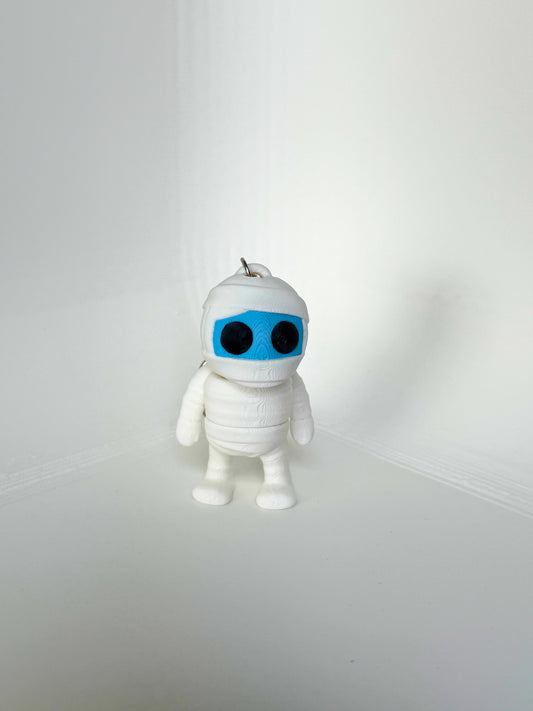 Duurzaam speelgoed: wit mummie sleutelhanger figuur met zwarte ogen en blauw gezicht, vooraanzicht
