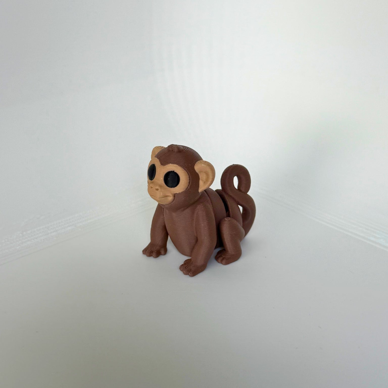 Duurzaam speelgoed: 3D-geprint bruin aapje met opgerolde staart en articulerende poten, zijaanzicht