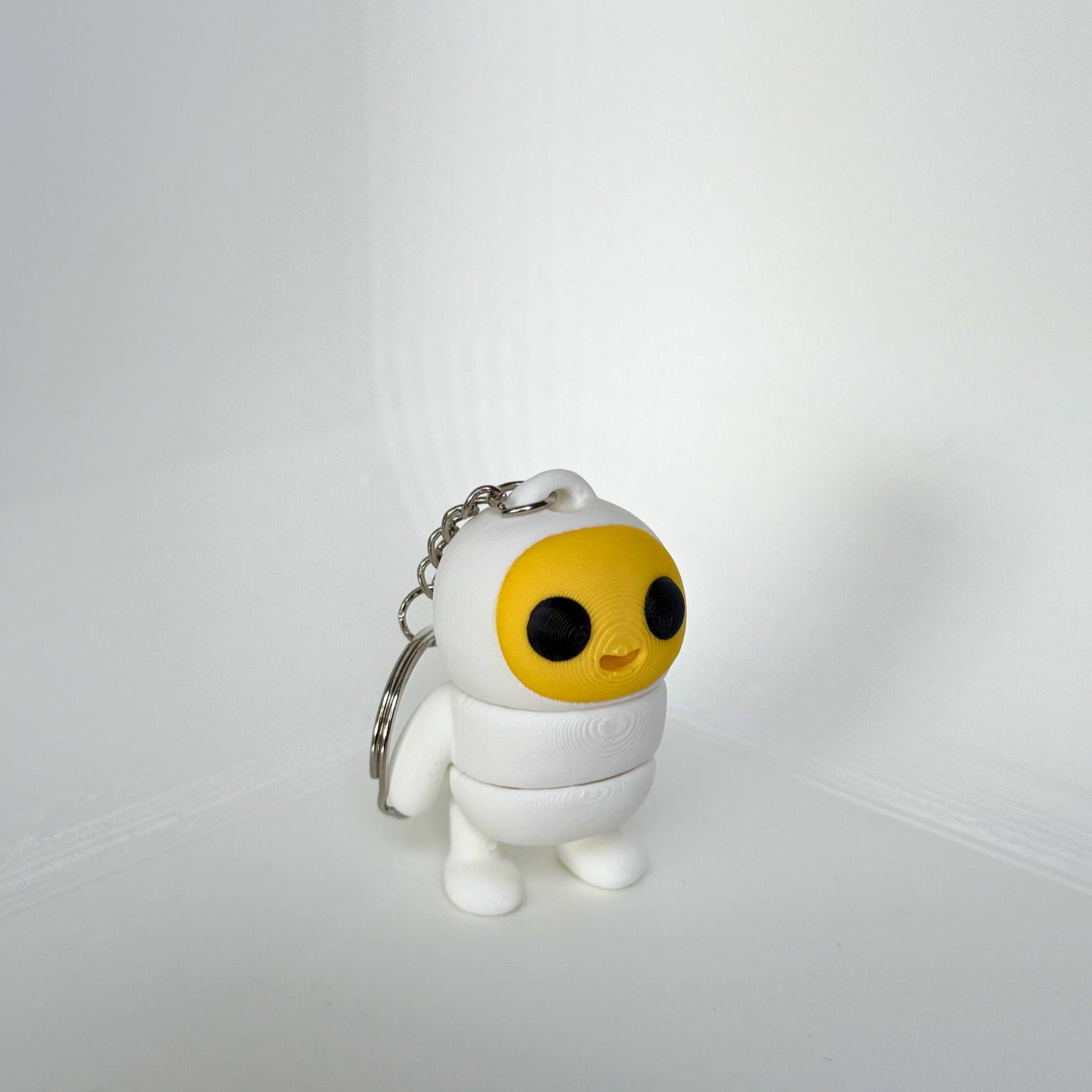 Kindvriendelijke sleutelhanger van Egg Boy – een schattig 3D-geprint figuur met een geel gezicht en witte outfit.