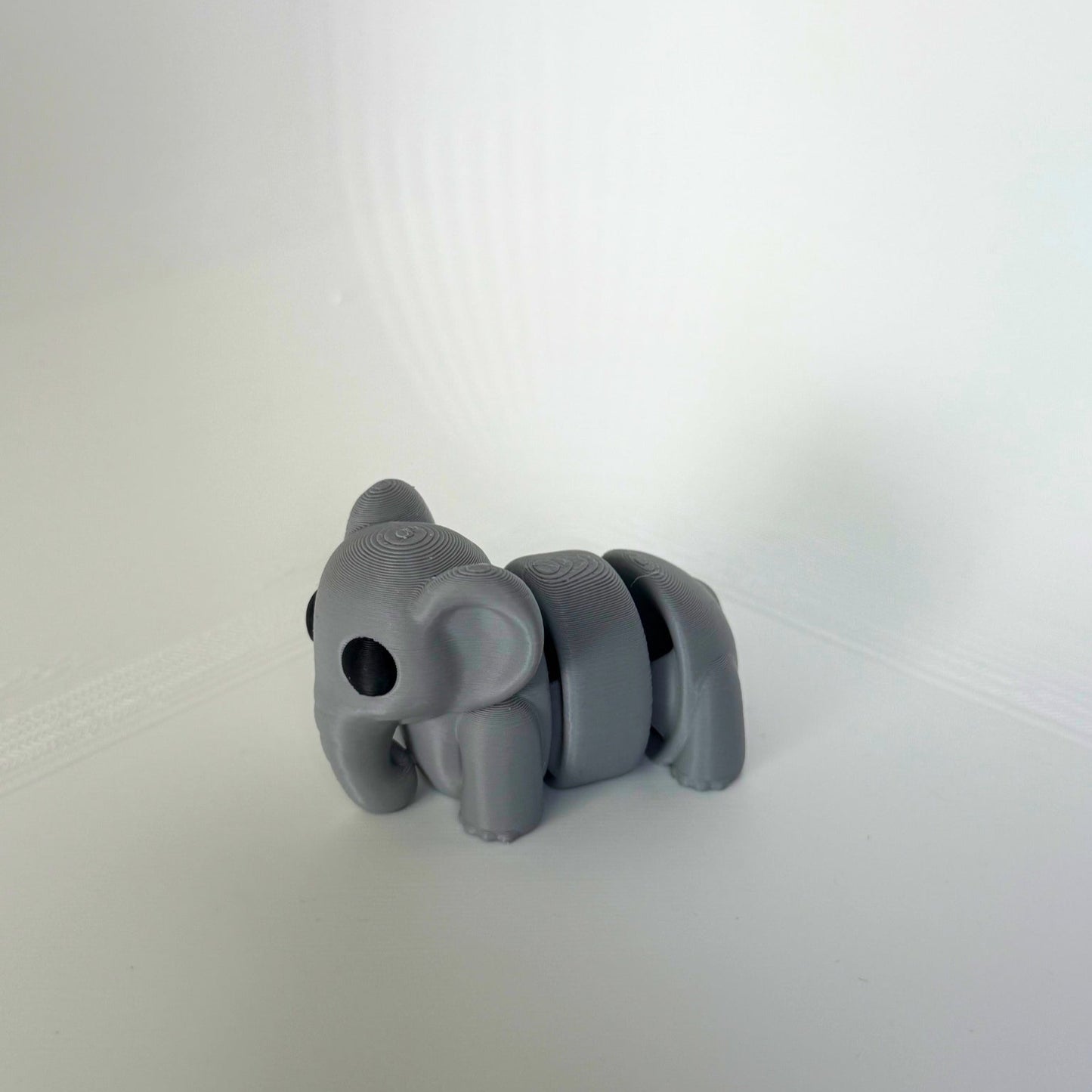Grijze 3D-geprinte olifant speelfiguur met schattige grote ogen, gefotografeerd van voren.