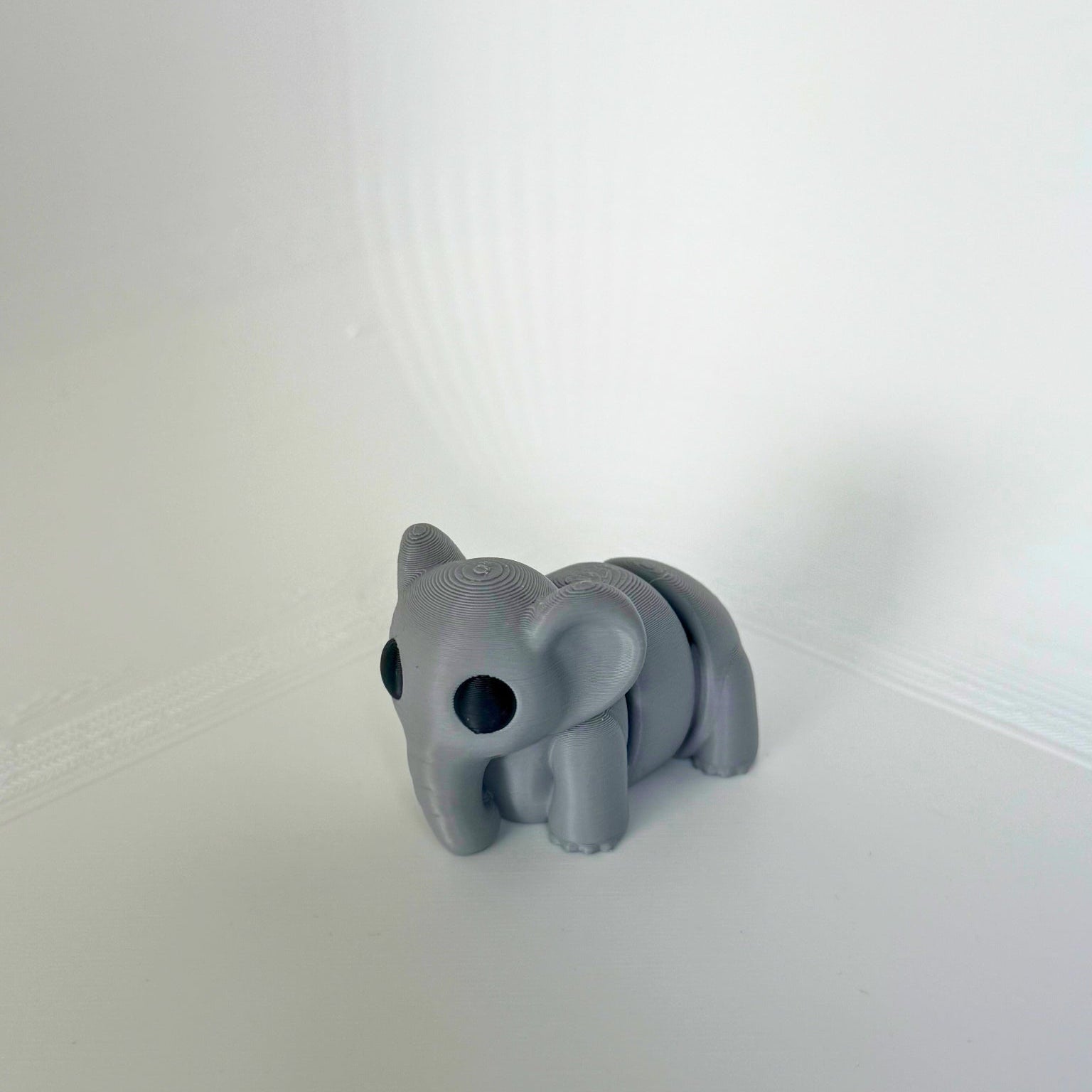 Zijaanzicht van een kindvriendelijk, beweegbaar olifantenspeeltje in grijze kleur