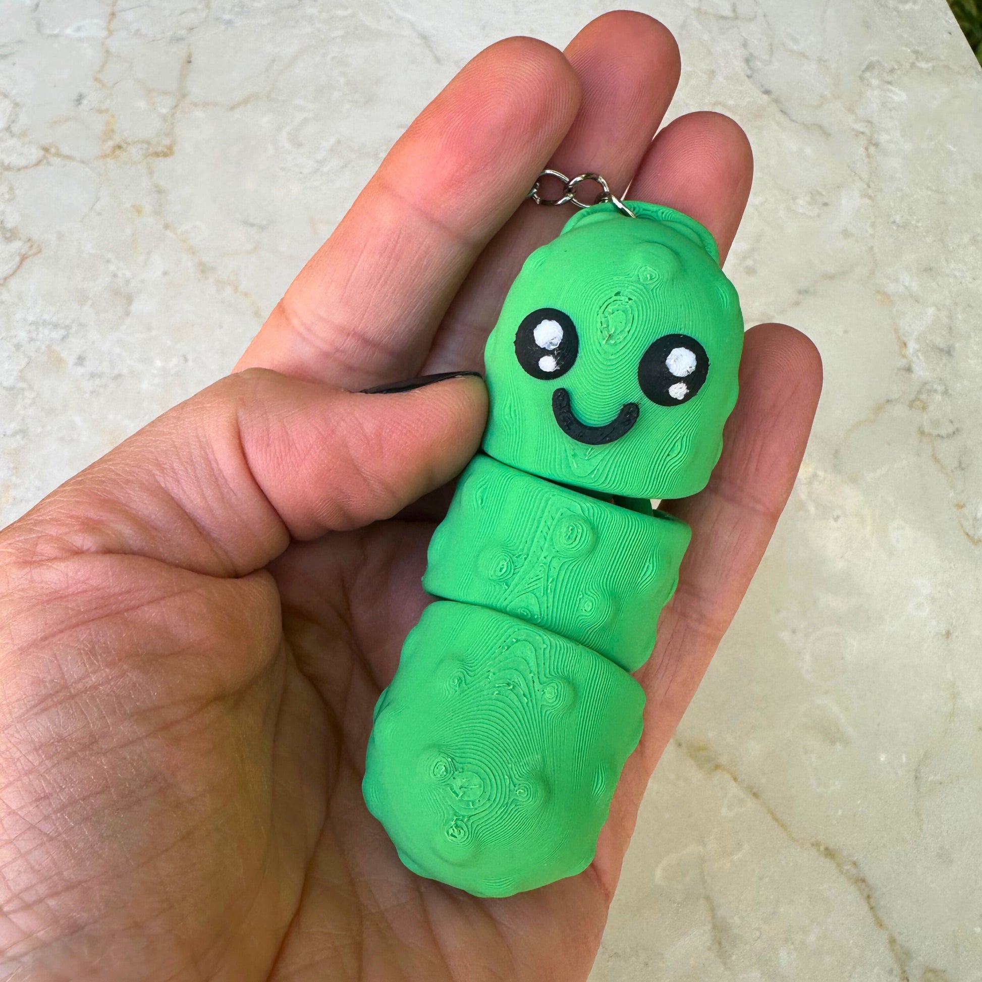 Close-up van 3D geprinte lachende augurk sleutelhanger, flexibel en grappig design.