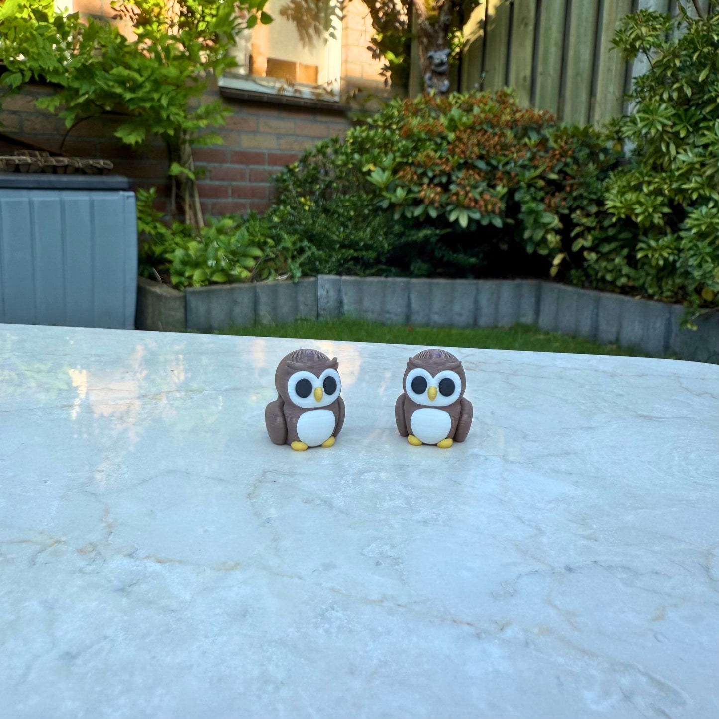 Twee bruine 3D geprinte flexibele uiltjes speelgoed, met grote ogen en beweegbare vleugels.