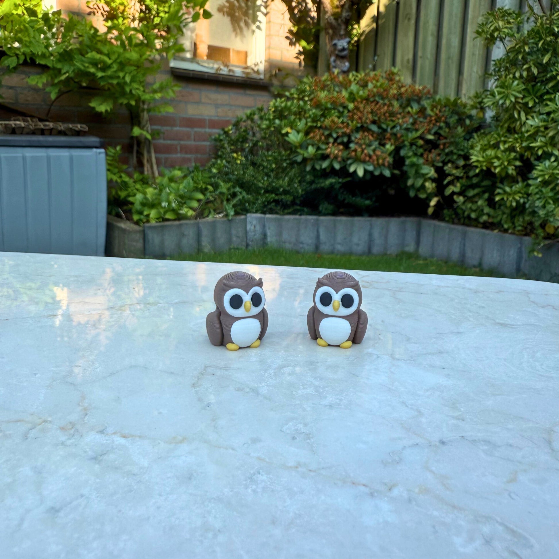 Twee bruine 3D geprinte flexibele uiltjes speelgoed, met grote ogen en beweegbare vleugels.