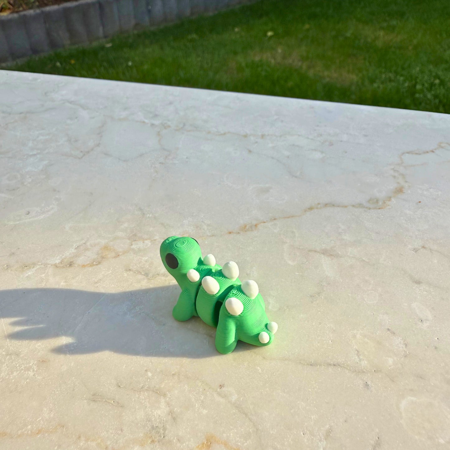 Detail van een 3D geprinte flexibele baby stegosaurus, focus op de rugplaten.