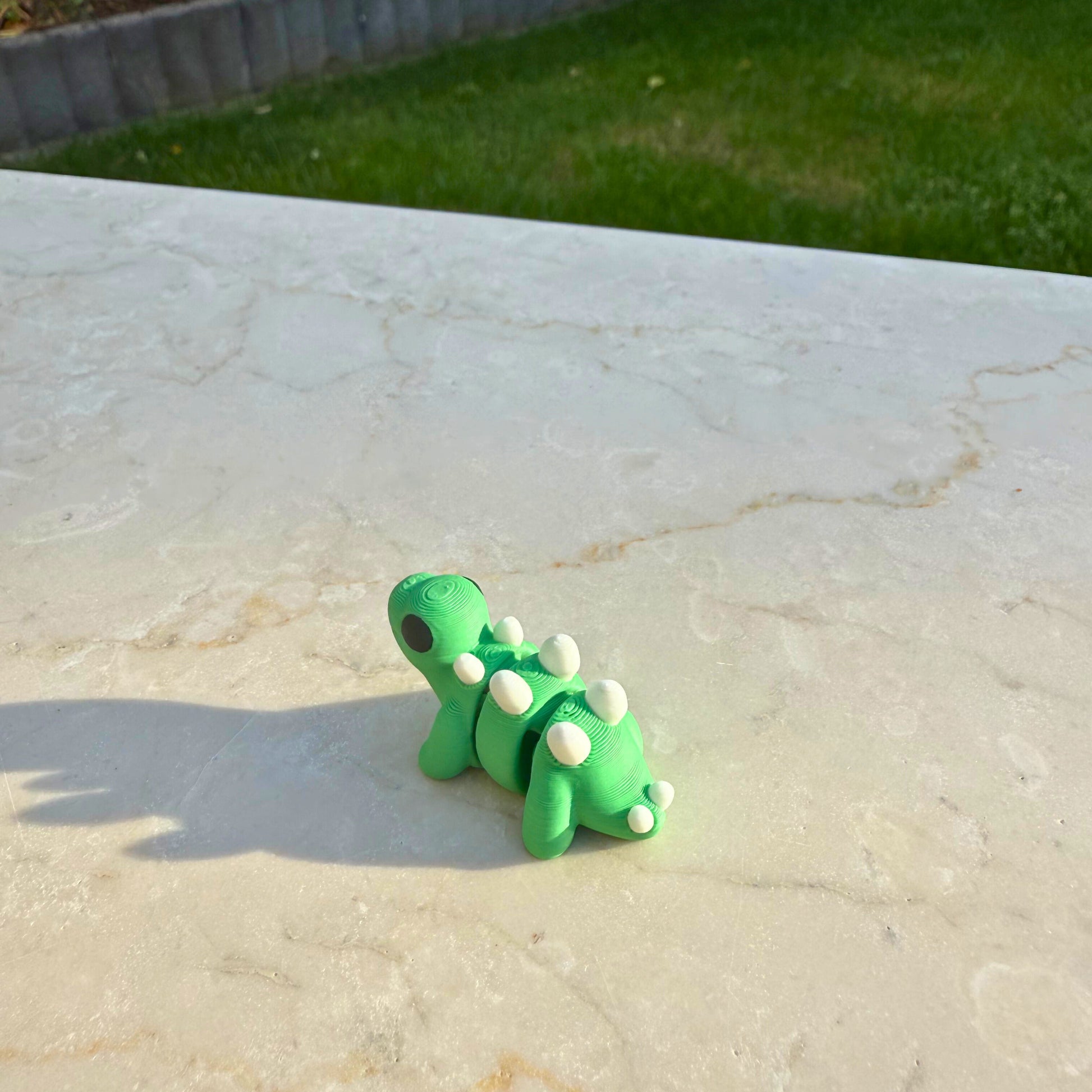 Detail van een 3D geprinte flexibele baby stegosaurus, focus op de rugplaten.