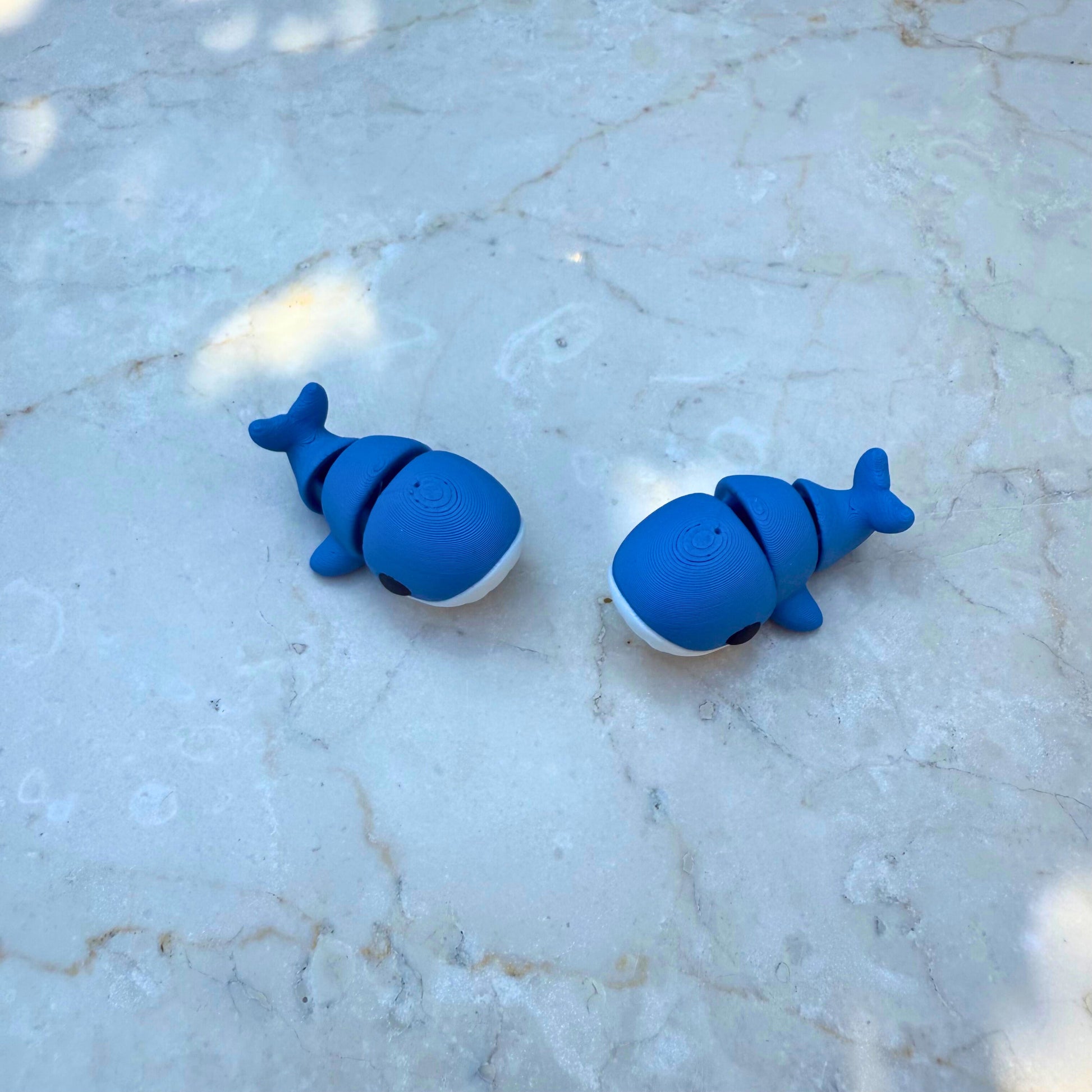 Detail van een blauw 3D geprint flexibel baby walvisje, toont de articulatie.