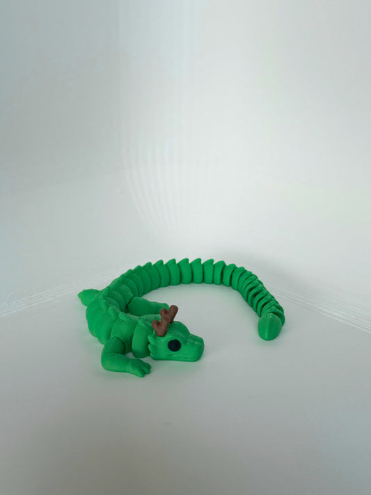 Speelse groene draak met bruine hoorns, volledig uitgestrekt op een witte achtergrond.