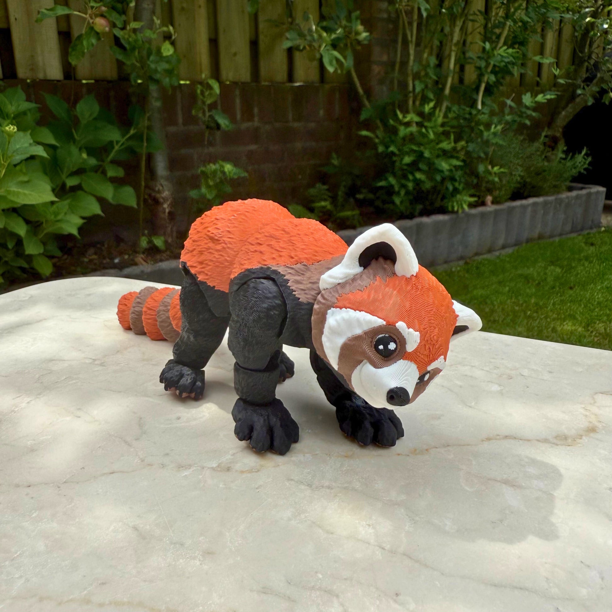 3D geprint flexibel rode panda speelgoed, achteraanzicht met geringde staart en beweegbaar lichaam.