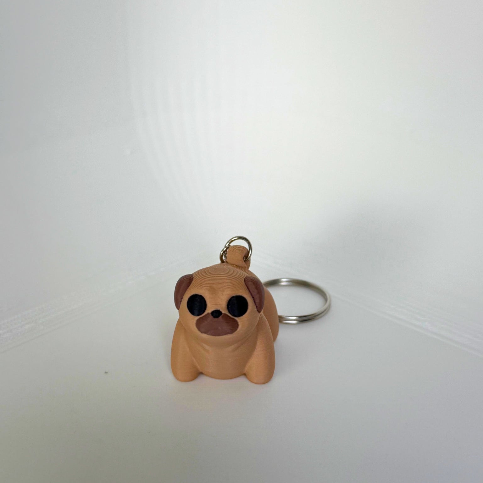 Beige mopshond speelgoedfiguur van PLA met sleutelhanger – 3D-print in vooraanzicht met zwarte ogen en bruine snuit
