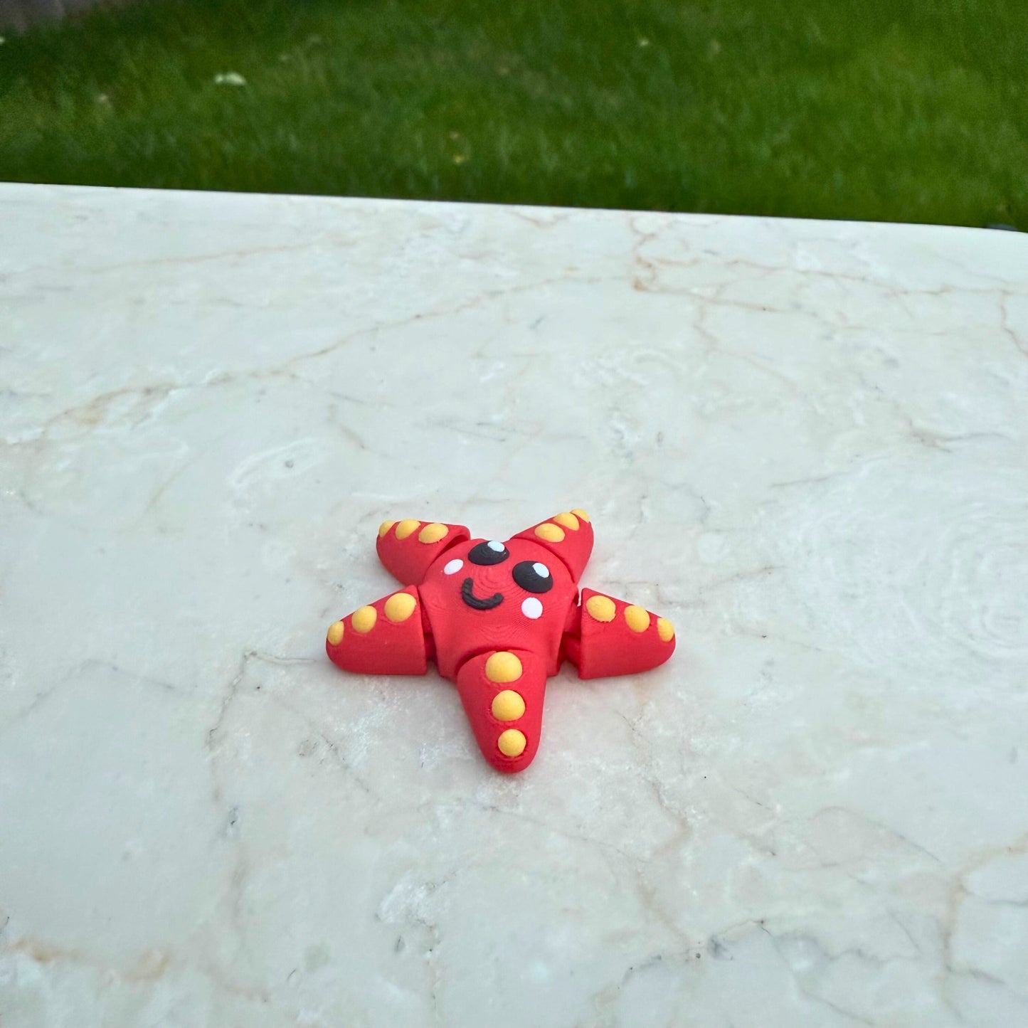 Schattig 3D geprint speelgoed zeesterretje, toont de articulatie en het vrolijke design.