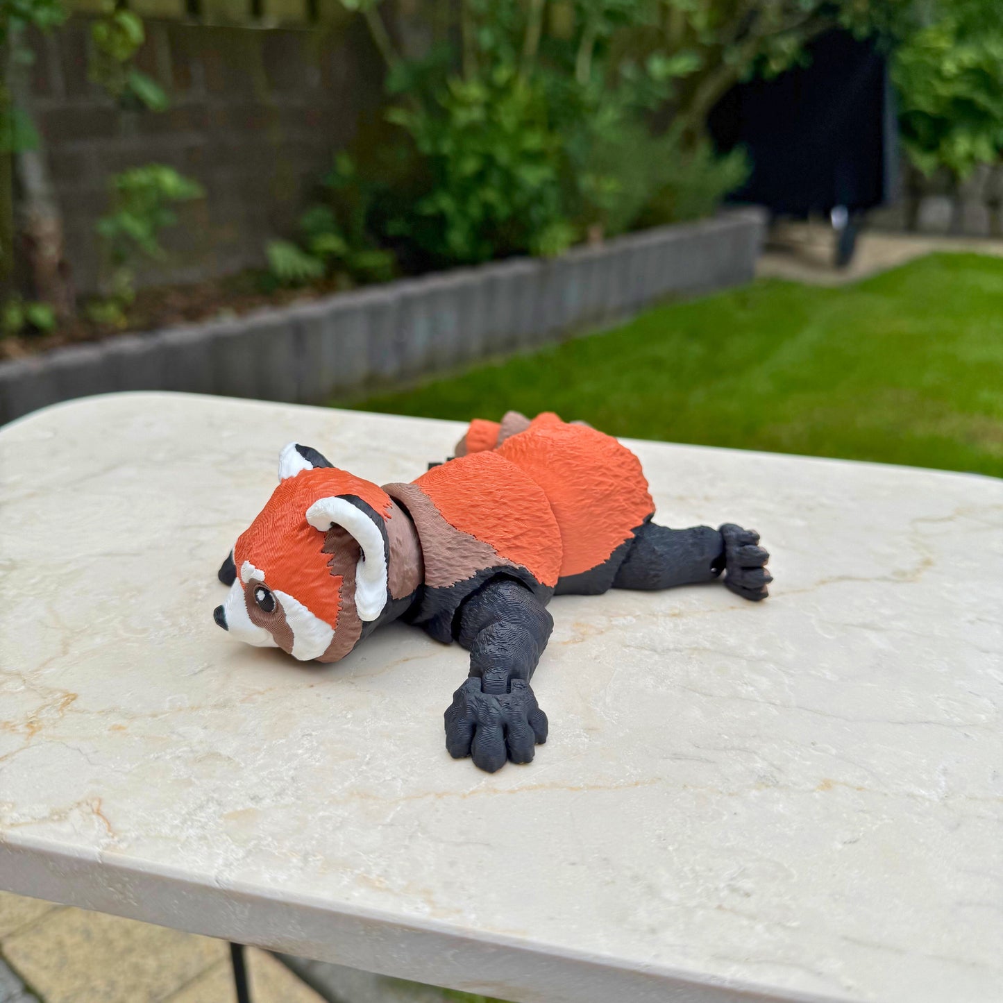 Vooraanzicht van een 3D geprinte speelgoed rode panda, toont het schattige gezicht en de articulatie.