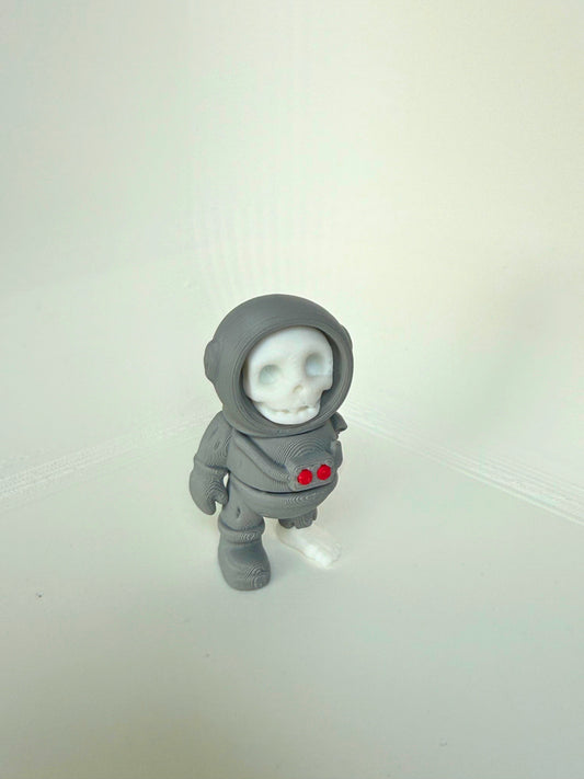 3D-printed dead astronaut toy seen from the side, featuring a skull face and detailed space suit with red chest lights.