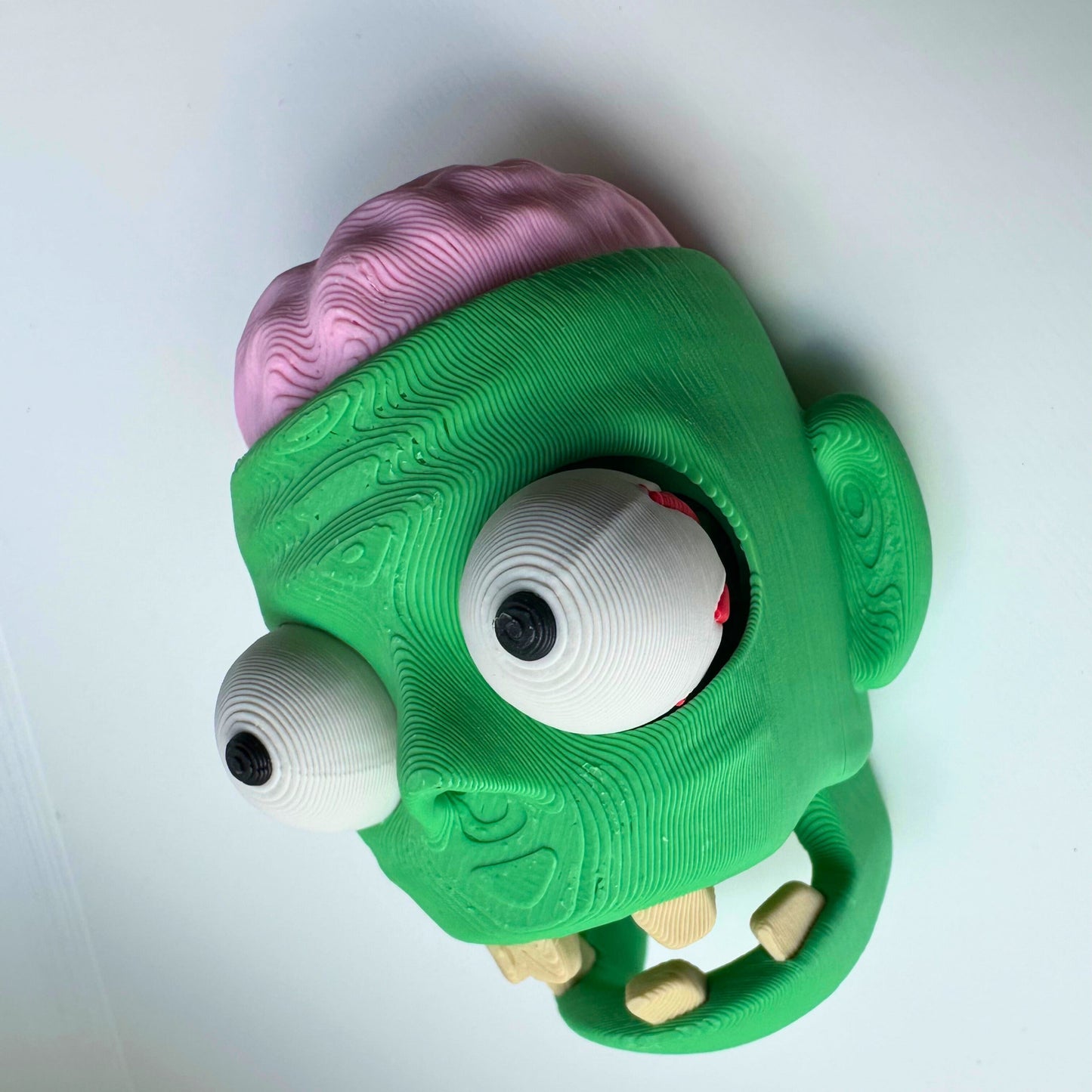 Interactief 3D geprint zombie hoofd fidget speeltje, met zichtbaar brein en ogen die kunnen bewegen.
