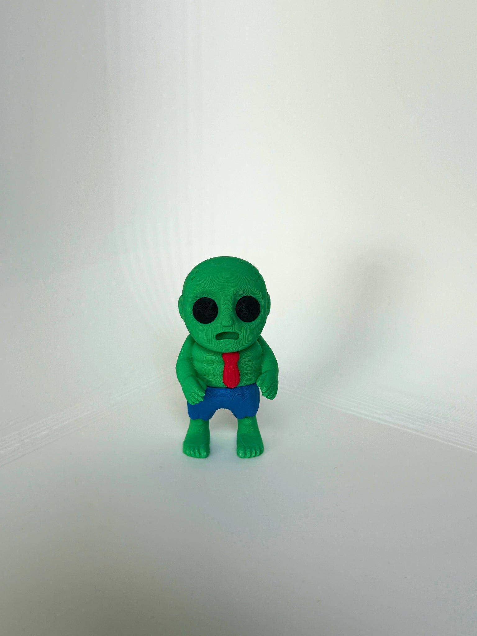 Kindvriendelijk 3D-geprint zombie speelfiguur in groene kleur met rode das en blauwe broek – voorkant